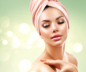 Spa Woman. Beautiful Girl After Bath Touching Her Face. Perfect Skin. Skincare. Young Skin, youth. Beauty female with a towel on her head pampering skin Pure Skin Aurora